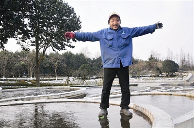 一名工人站在杭州花圃水花台的冰面上。 